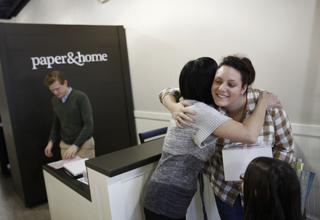 Brooke Coxen hugs customer Kayla Geraci, right, at paper & home in Las Vegas Tuesday, Nov. 19, 2013
